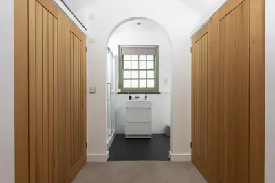 a bathroom with two wooden doors and a sink at Fairings, St Ives in St Ives