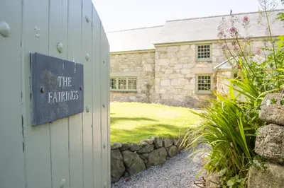 a stone house with a sign that reads the ferns at Fairings, St Ives in St Ives