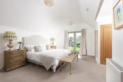 a white bedroom with a bed and a table at Fairings, St Ives in St Ives