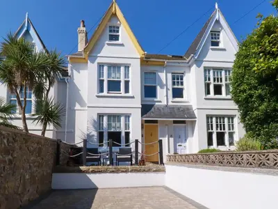 a white house with a wall and trees at Sea Candy in St Ives