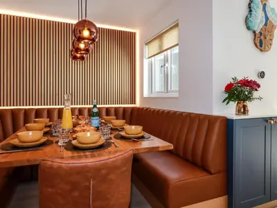 a dining room with a table and a brown couch at Sea Candy in St Ives