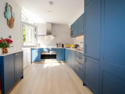 a kitchen with blue cabinets and a wooden floor at Sea Candy in St Ives