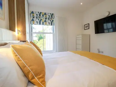 a bedroom with a large white bed with a window at Sea Candy in St Ives