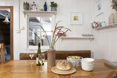 a table with a vase of flowers and wine glasses at No 1 St Eia, St Ives in St Ives