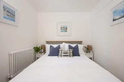 a bedroom with a white bed with blue pillows at No 1 St Eia, St Ives in St Ives