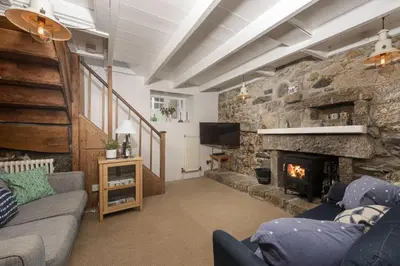 a living room with a stone wall with a fireplace at No 1 St Eia, St Ives in St Ives