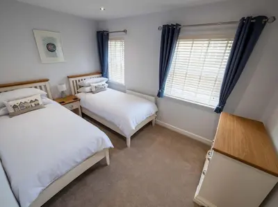 a bedroom with two beds and two windows at Padstow Escapes - Trenemere in Padstow
