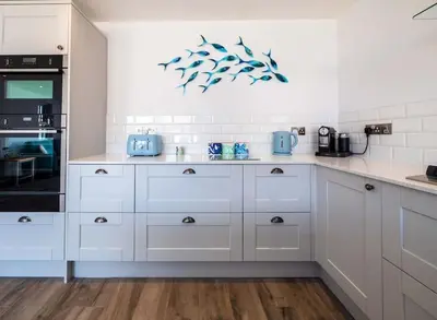 a kitchen with white cabinets and blue appliances at Padstow Escapes - Trenemere in Padstow