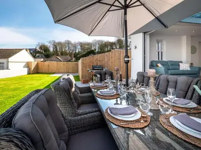 a table with chairs and an umbrella in a backyard at Padstow Escapes - Trenemere in Padstow