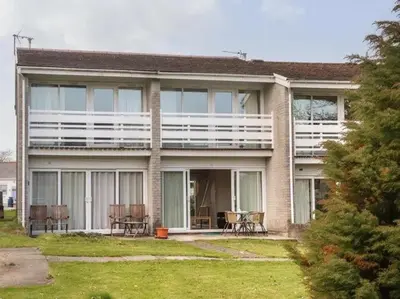 a house with windows and chairs in a yard at 2 Bed Cottage Sleeps 5 - Pets Allowed in Newquay