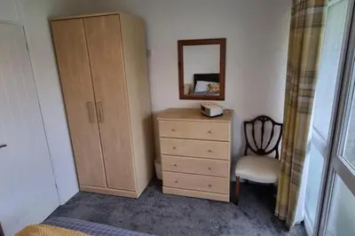 a bedroom with a dresser and a mirror and a chair at 2 Bed Cottage Sleeps 5 - Pets Allowed in Newquay