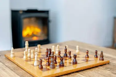 a wooden chess board with chess pieces on a table with a fireplace at 5 Bed in Padstow oc-s29853 in Padstow