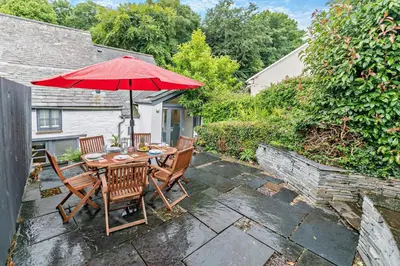 a patio with a table with a red umbrella at 5 Bed in Padstow oc-s29853 in Padstow