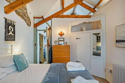 a bedroom with a large white bed and a dresser at Cobble by Together Travel - Luxury Cornish Countryside Retreat in Bodmin