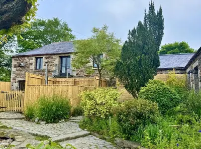 a house with a wooden fence in a garden at Cobble by Together Travel - Luxury Cornish Countryside Retreat in Bodmin