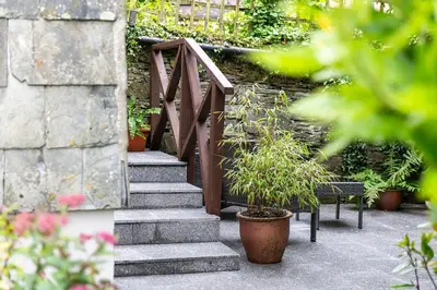 a stairway with a wooden rail and a plant at Zen Den Cornwall in Boscastle
