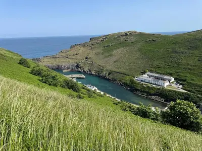 a body of water with a house on a hill at Zen Den Cornwall in Boscastle