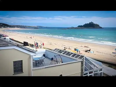 a view of a beach with people on the sand at Beach House Apartment, Across St Michaels Mount in Marazion