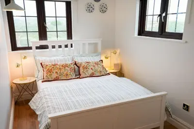 a white bed in a room with two windows at Beach House Apartment, Across St Michaels Mount in Marazion