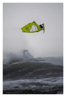 a kite flying in the air over the ocean at Beach House Apartment, Across St Michaels Mount in Marazion