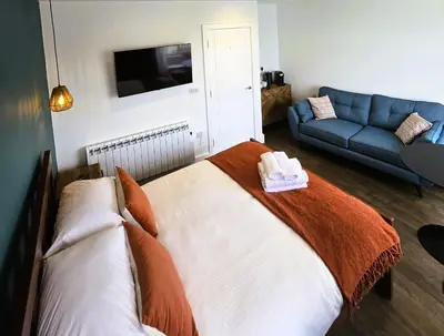 a bedroom with a bed and a blue couch at Premier 4 - Stunning Suite, beautiful sea views in St Ives