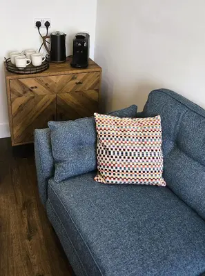 a blue couch with a pillow next to a wooden dresser at Premier 4 - Stunning Suite, beautiful sea views in St Ives