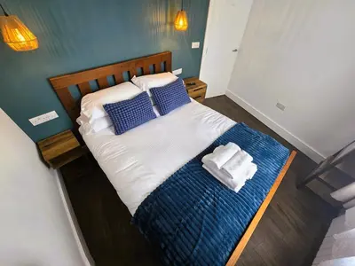 a bed with blue and white sheets and pillows at Premier 4 - Stunning Suite, beautiful sea views in St Ives