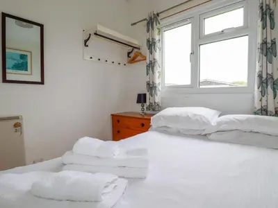 a bedroom with two beds with white sheets and a window at Constantine Bay in Padstow