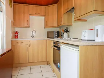 a kitchen with wooden cabinets and a white appliance at Newtrain Bay in Padstow