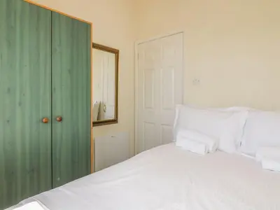 a bedroom with a bed with white sheets and a mirror at Warren Cove in Padstow