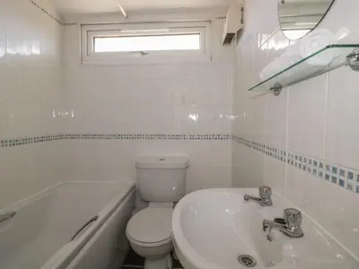 a white bathroom with a toilet and a sink at Warren Cove in Padstow