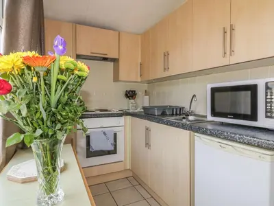 a kitchen with a vase of flowers on a table at Warren Cove in Padstow
