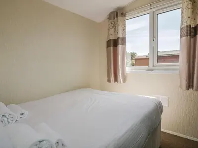 a bedroom with a white bed and a window at Warren Cove in Padstow
