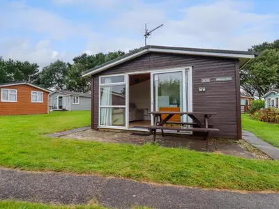 a tiny house with a patio and a table at Hawker's Cove in Padstow