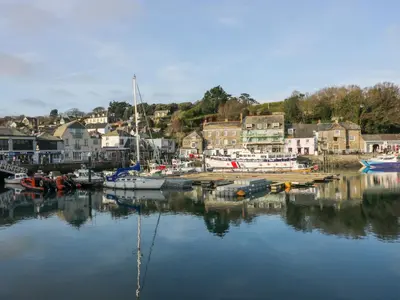 a group of boats docked in a harbor with a town at Hawker's Cove in Padstow