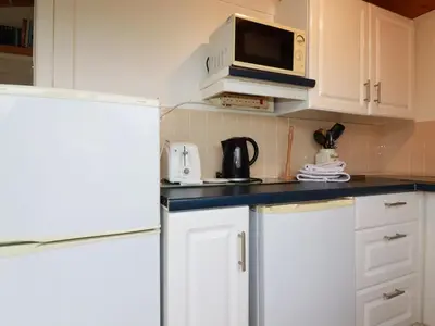 a kitchen with white cabinets and a microwave at Hawker's Cove in Padstow