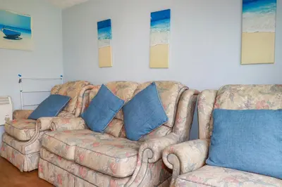 a couch with blue pillows in a living room at High Cove in Padstow