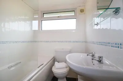 a white bathroom with a toilet and a sink at High Cove in Padstow
