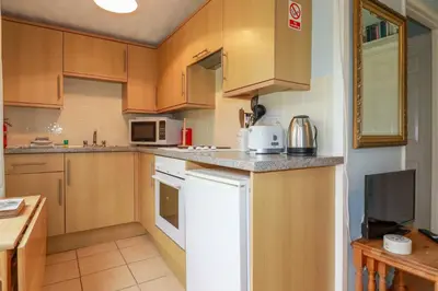 a kitchen with wooden cabinets and a white refrigerator at High Cove in Padstow