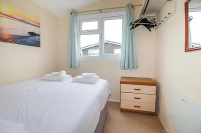 a bedroom with a white bed and two windows at High Cove in Padstow