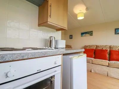 a kitchen with a stove top oven next to a couch at Fox Cove in Padstow