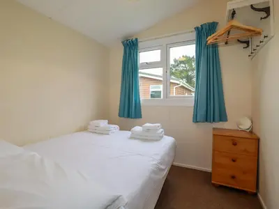 a bedroom with a bed and a window with blue curtains at Fox Cove in Padstow