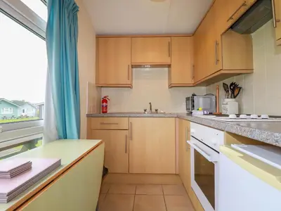 a kitchen with wooden cabinets and a large window at Fox Cove in Padstow