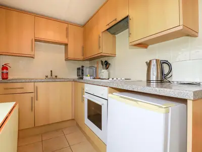 a kitchen with wooden cabinets and white appliances at Fox Cove in Padstow