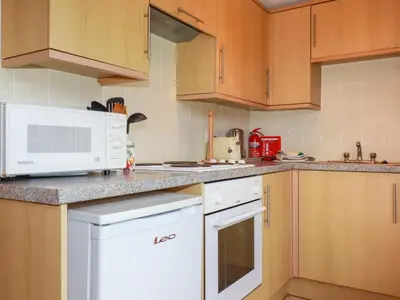 a kitchen with wooden cabinets and a white microwave at Pepper Cove in Padstow