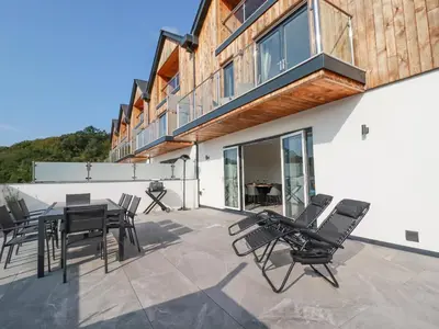 a patio with chairs and a table and a building at Carnon Gwel, Devoran in Truro