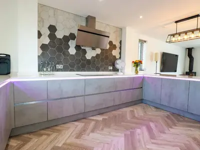 a kitchen with purple cabinets and a tv on a wall at Carnon Gwel, Devoran in Truro