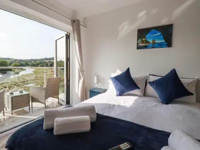 a bedroom with a bed and a large window at Carnon Gwel, Devoran in Truro