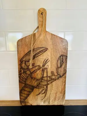 a wooden cutting board with a drawing on it at Willow Lodge in Helston