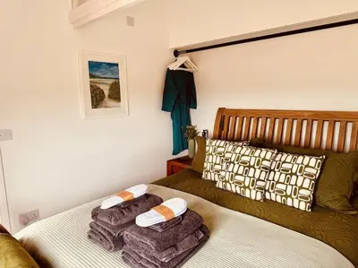a bedroom with a bed with towels on it at Willow Lodge in Helston